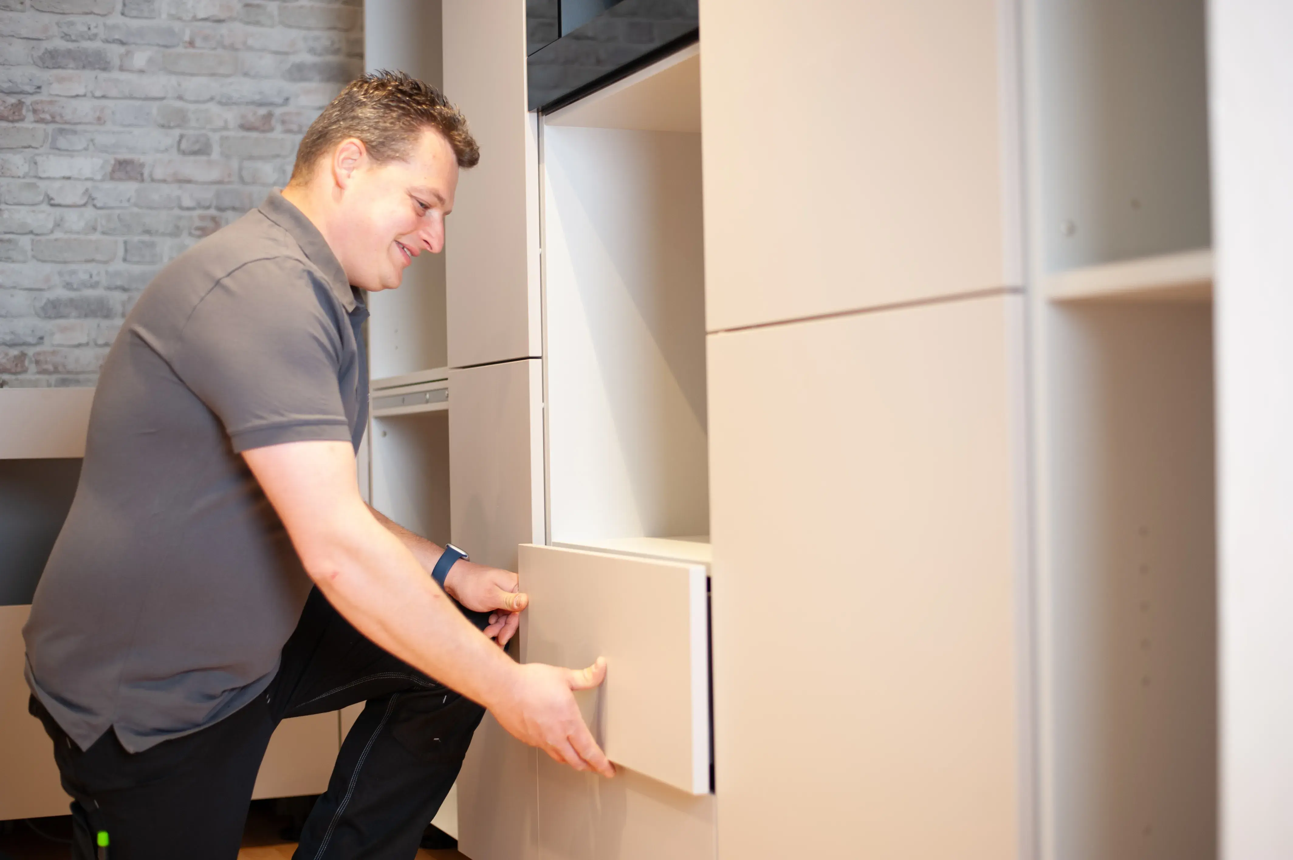 Florian Jacobi montiert eine Schranktür an einem hellen Einbauschrank.