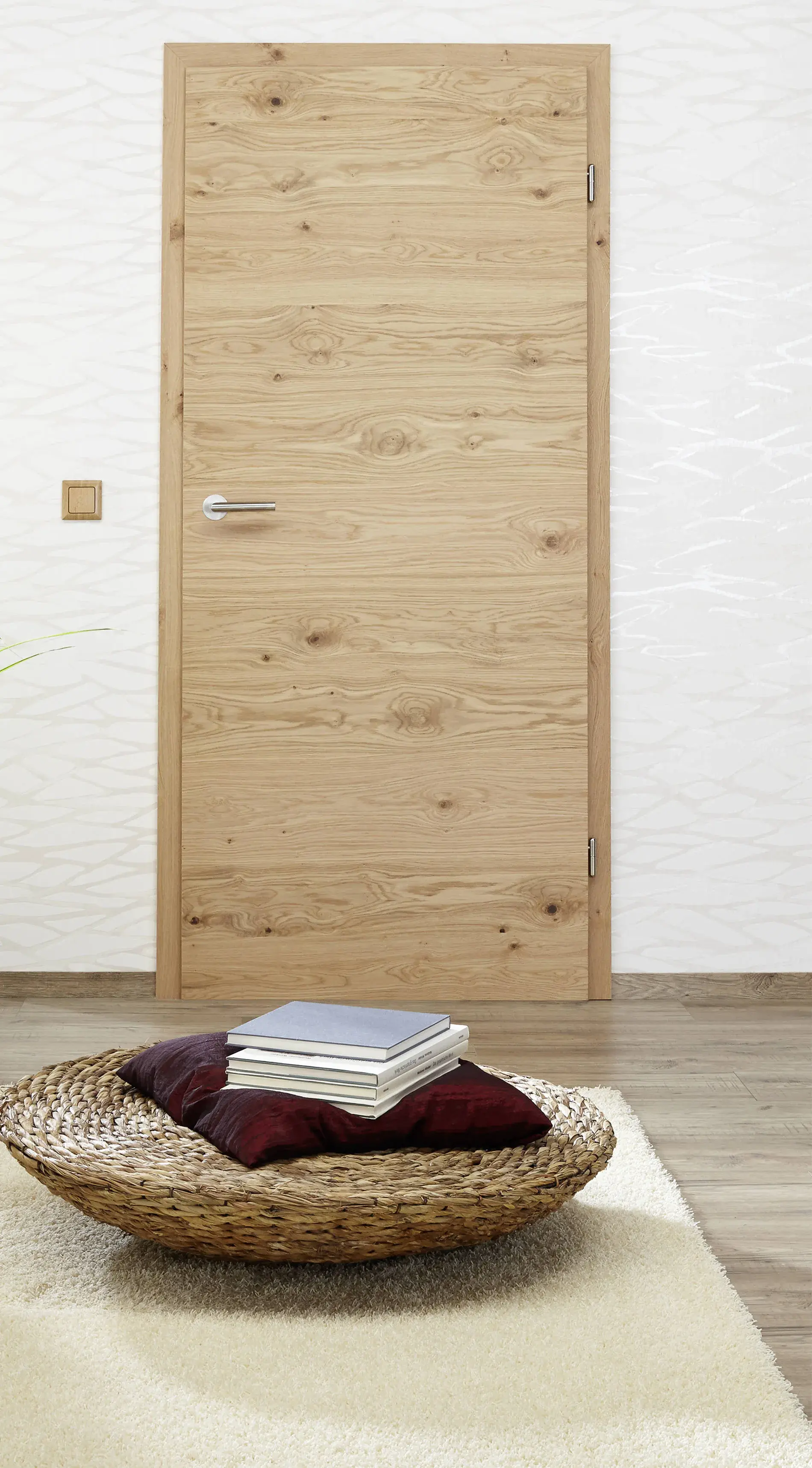 Holztür in modernem Raum, davor ein Korb mit Kissen und Büchern auf Teppich.