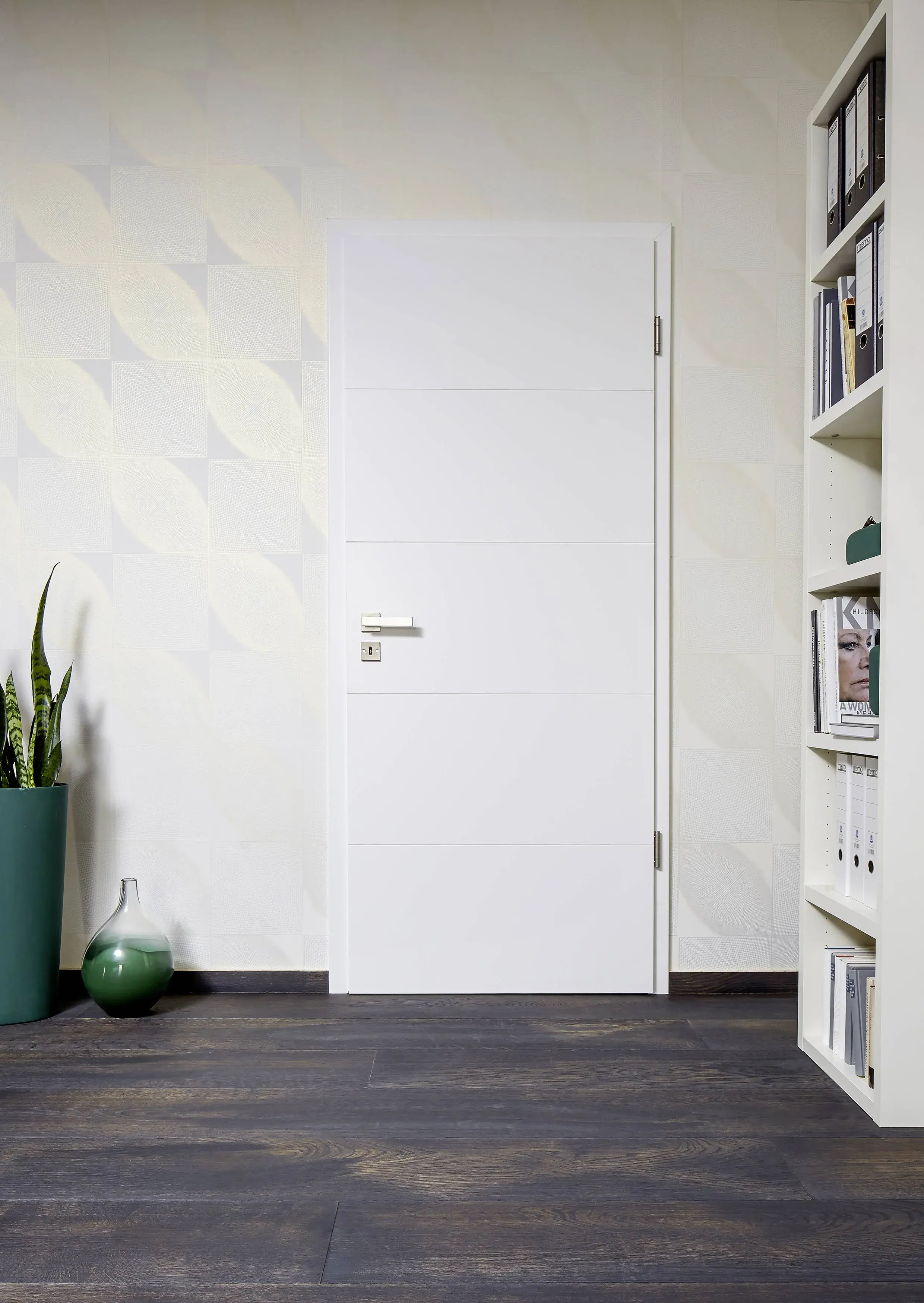 Weiße Tür in modernem Raum mit Regal, Pflanze und dunklem Holzboden